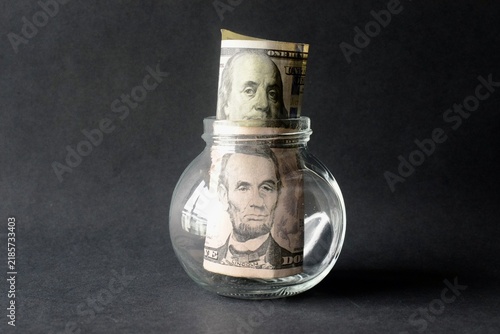 Obraz na plátně US dollar bill with Benjamin Franklin portrait inside a clear glass jar on a black background