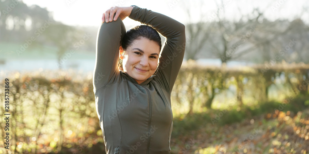 Fototapeta premium Athletic woman is doing stretching exercises after workout, training and running on a beautiful winter morning, panoramic view 