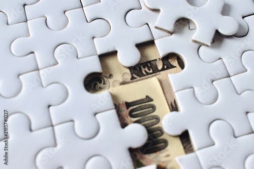 Cuadro en lienzo High-angle close-up of Japanese yen banknotes visible through a missing piece in a white jigsaw puzzle, illustrating financial solution and hidden wealth concepts