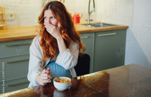 Quadro su tela Pregnant woman experiencing nausea and food aversion while eating a meal at home, illustrating morning sickness and common pregnancy symptoms