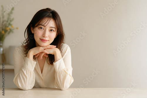 テーブルに肘をつき微笑む清潔感ある日本人女性