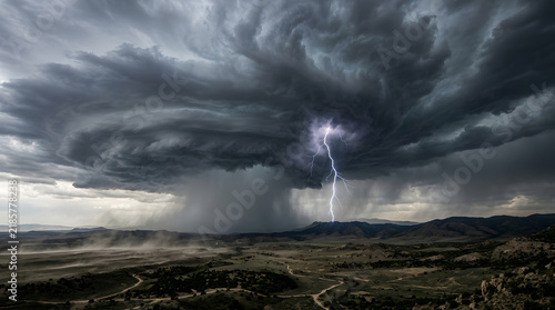 Dramatic supercell thunderstorm with a powerful lightning strike over a vast desert landscape.