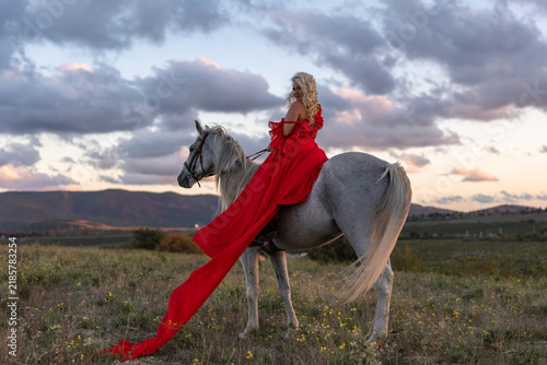 Canvas Print Woman horse dress riding elegant white steed in dramatic sunset field