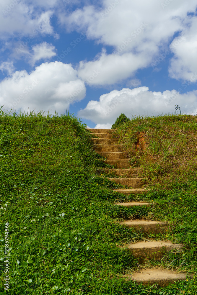Obraz premium Stone steps leading up grassy hill under blue sky