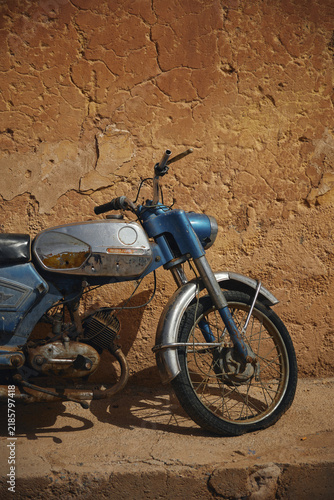 Konstfotografi Front detail of a parked vintage blue moped against an adobe wall