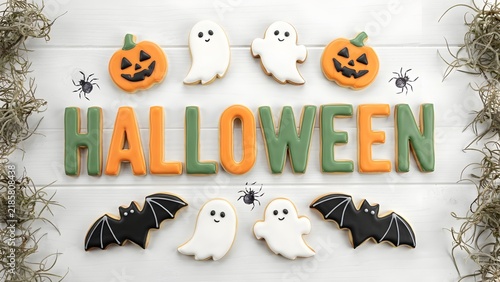 Halloween sugar cookies on white wood. Iced cookies shaped like pumpkins ghosts and bats. Festive holiday treats for autumn celebrations