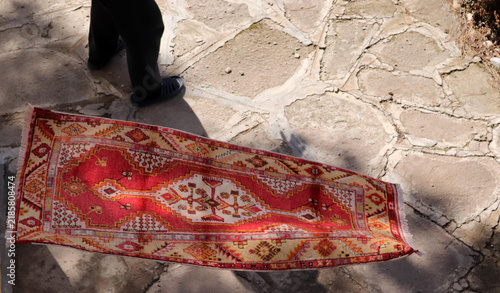 The shopkeeper is putting on a show to sell carpets to customers. A flying carpet.