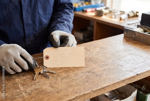 Locksmith Preparing Blank Identification Tag for Metal Keys at Workshop Bench