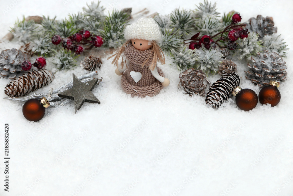 Fototapeta premium Christmas decoration featuring a small doll, pine cones, twigs, red berries, and Christmas baubles on snow, with copy space.