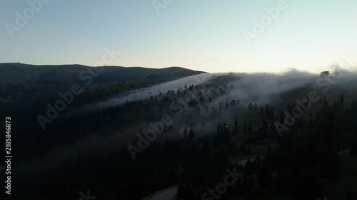 Smog on mountains with trees. Clouds move over the forest in evening time. Mystery view.  A view of mountains shows clouds moving over tall trees This location has a mixture of greenery and mist roll