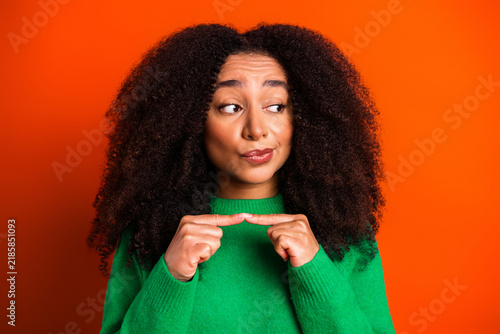 Konstfotografi Young woman in green sweater pointing at herself with a doubtful, hesitant expre