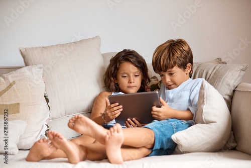 Fotografie Children, siblings and watching movie in home with tablet, internet connection and bonding together