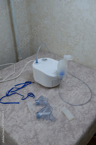 Medical compressor nebulizer machine with air tubing, inhalation chamber, masks, and accessories laid on a table. Respiratory treatment, asthma healthcare equipment, and medical technology concept