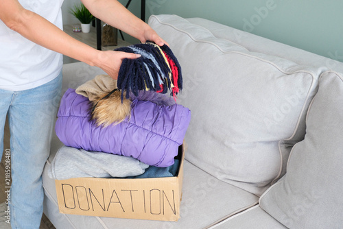 Donation box with winter clothes. The volunteer puts the different warm garment into a cardboard box.
