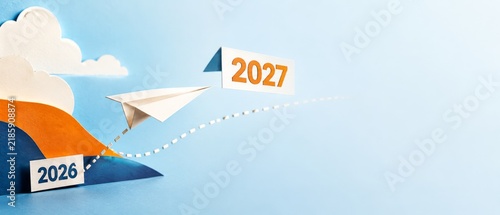 Paper airplane flying from 2026 to 2027 in blue sky background, new year transition