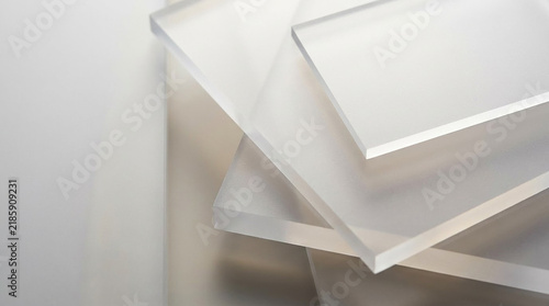 Stacked sheets of transparent acrylic glass on a white surface with polymethyl methacrylate transparent material clear sheets stacked layers industrial material geometric shapes