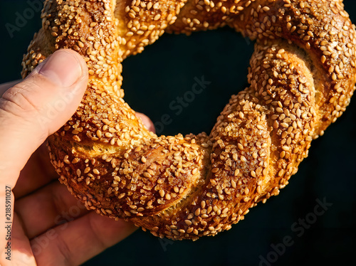 Hand holding a fresh sesame bagel bread ring