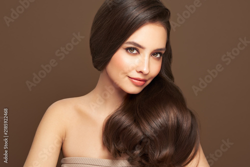 Brunette girl with perfect makeup. Smiling beautiful model woman with long curly hairstyle. Care and beauty hair products