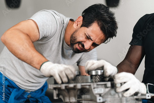 Fotografie Electric vehicle battery car service Man straining while repairing industrial ma