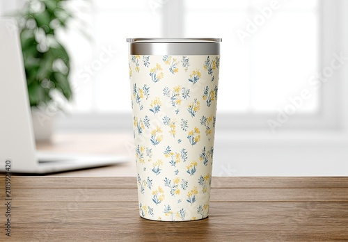 A tumbler with a delicate floral pattern sits on a wooden surface