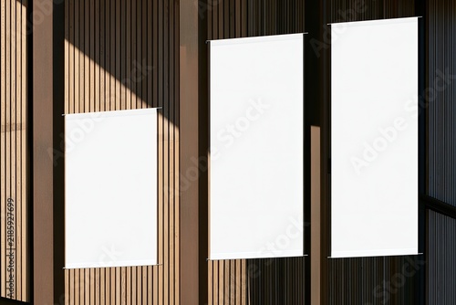 Three blank white banners hang vertically against a wooden textured wall