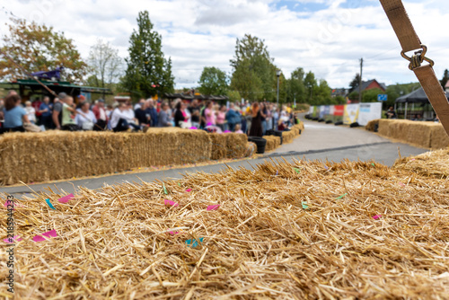 Obraz na plátně Hay bales line roadside race course while spectators gather behind safety barriers during outdoor soapbox racing event