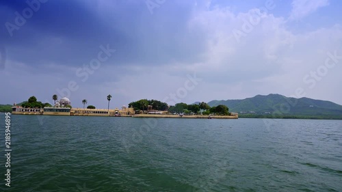 Udaipur, Rajasthan, India: Wide view of Jag Mandir island palace against the Aravalli hills, surrounded by the rippling water of Lake Pichola.