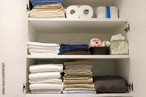 Organized bathroom cabinet shelves with folded linen stack.