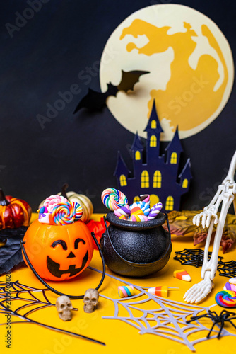 Halloween candy buckets with spooky decorations on yellow background