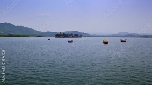 Udaipur, Rajasthan, India: Several yellow-roofed boats dot Lake Pichola with Jag Mandir island palace and layered hills in the background.