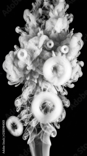 White smoke rings floating in a dark vertical composition