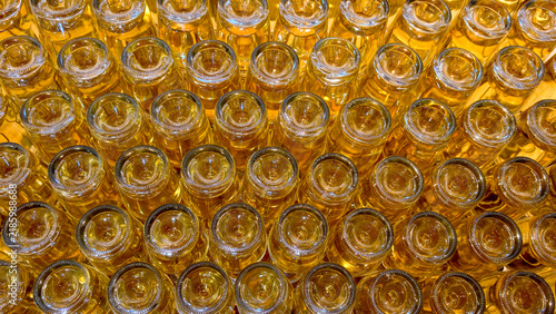 Bild auf Leinwand Numerous glass bottles filled with golden liquid, creating an organized pattern,