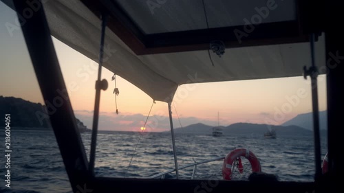 Cruising on a boat during sunset with soft waves and distant hills visible on the horizon near a coastal area