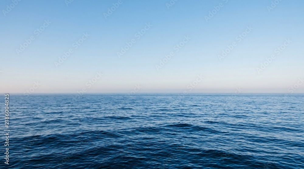 Obraz premium Vast minimalist seascape with deep blue waves meeting a clear gradient sky at a straight horizon, calming infinite marine atmosphere