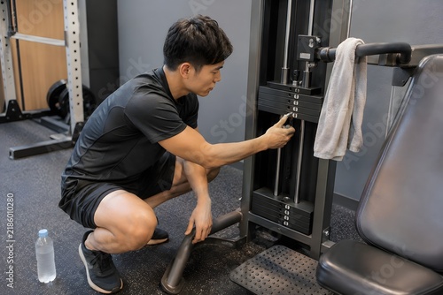 Plakat ジムでマシンを調整する男性
