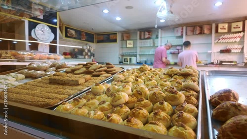 Bakery display shows different baked goods with two workers preparing items in the background during the day
