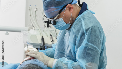 Fotografía Male patient receiving dental treatment in clinic, mouth open while dentist uses