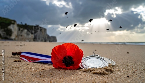 Poppy and medals on a beach with paratroopers in the sky, a poignant reminder of sacrifice and remembrance