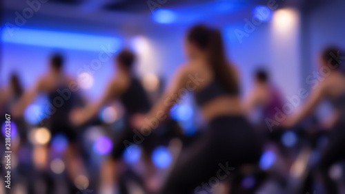 Blurred view of a group of people on stationary bikes during a dynamic indoor spin class