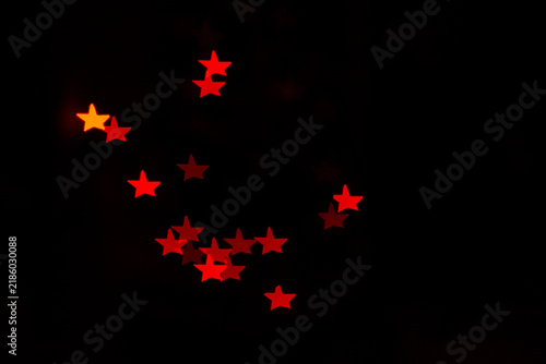 Red star shaped bokeh lights glowing against dark abstract background