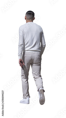 jeune homme vu de dos en tenue blanche décontractée, il marche son smartphone dans la main, pull blanc, pantalon clair et baskets blanches, journée ensoleillée