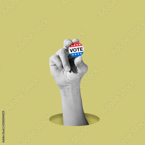black and white man holding a colorful vote badge