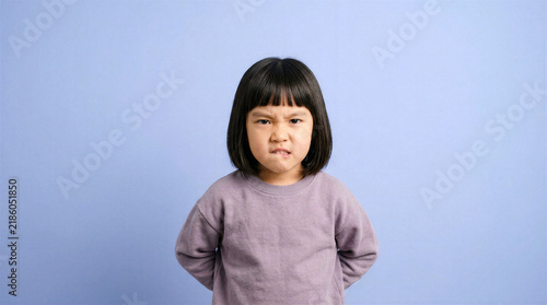 Young girl with a stubborn pout and biting her lip, looking annoyed
