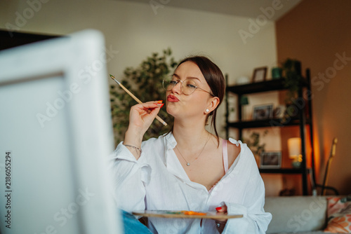 Fotografie Woman artist holding paintbrush pouting for selfie portrait