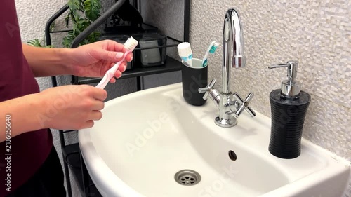 Woman's hand takes toothbrush from glass in bathroom at home. Health care,dental hygiene,morning routine