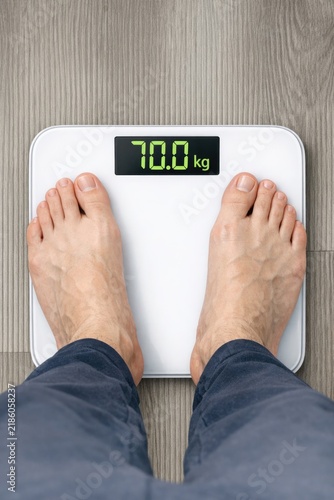 A person stands on a scale with their feet on the platform, measuring their weight