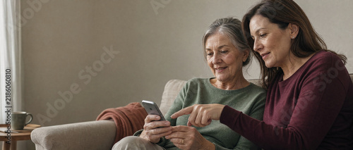 Senior Woman Learning Mobile Banking with Her Adult Daughter