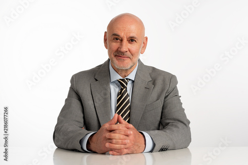 Studio portrait of a confident mature businessman wearing grey suit and tie against isolated background