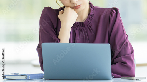 Obraz na płótnie パソコンを使いながら考える女性・ビジネスウーマン, Businesswoman Thinking While Using a Laptop