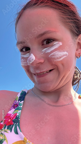 Teenager girl applying facial sunscreen protection for melanoma and sunburn prevention.